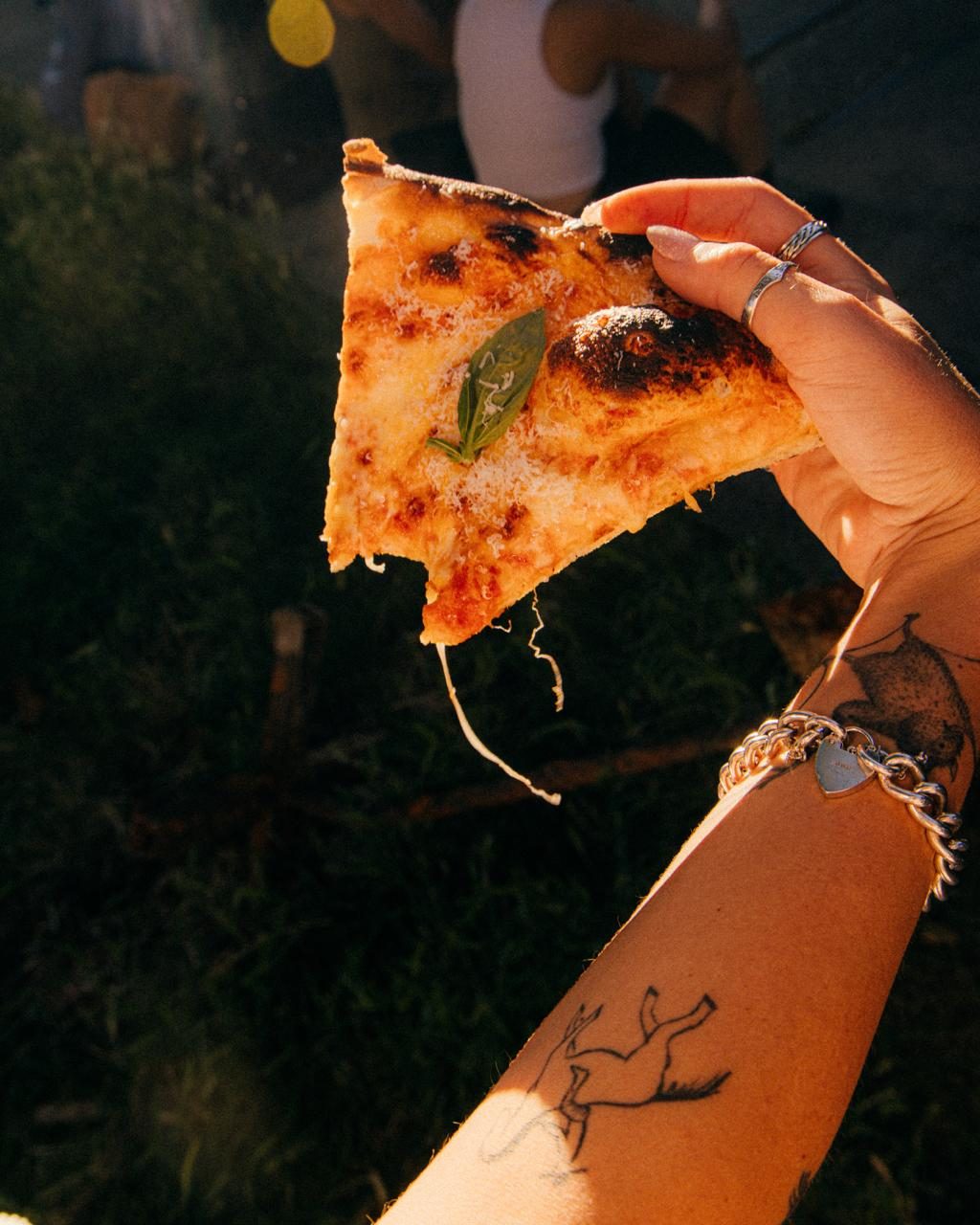 A NO FLOP margherita slice held up in the evening sun